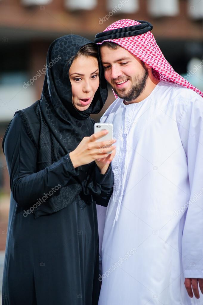 Moderm Arabic couple poses outdoors.
