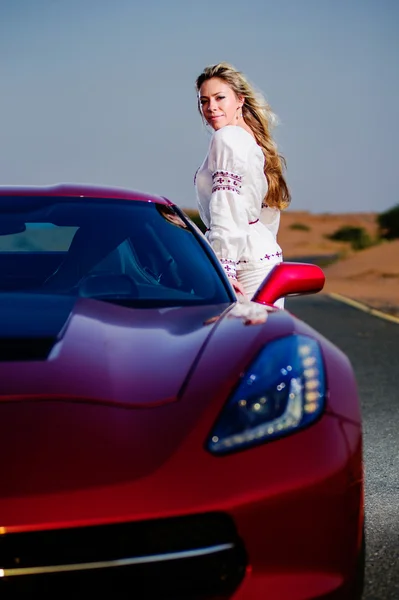 Portrait of happy woman standing in front of convertible car in desert. — Stock Photo, Image