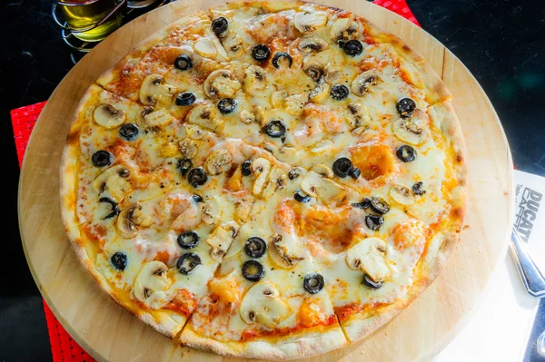 Pizza italiana con varios tipos de carne y aceitunas negras —  Fotos de Stock