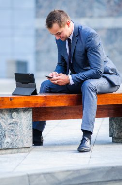 Yang işadamı açık havada tablet bilgisayarla çalışır.