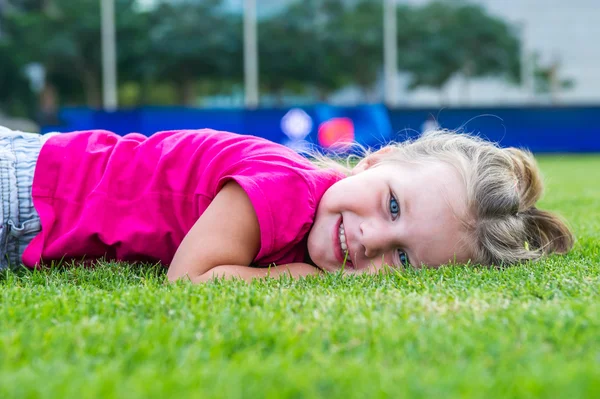 Small cute European girl posing  in the green grass. — Stock Photo, Image