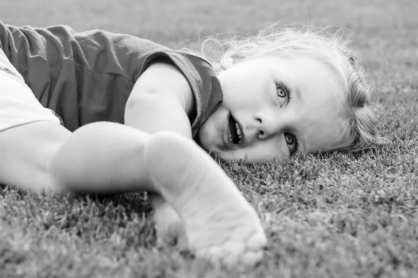 Small cute European girl posing  in the green grass. — Stock Photo, Image