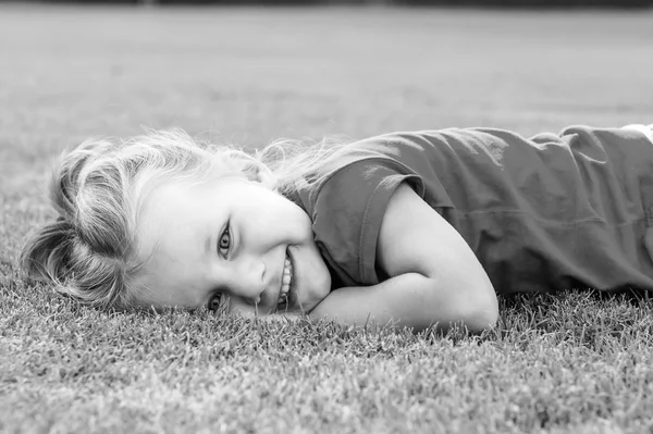 Kleines süßes europäisches Mädchen posiert im grünen Gras. — Stockfoto