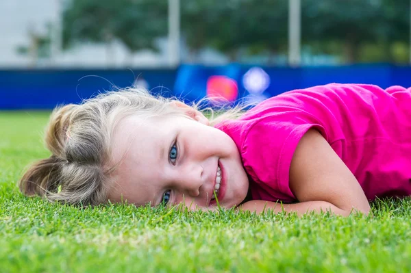 Small cute European girl posing  in the green grass. — Stock Photo, Image