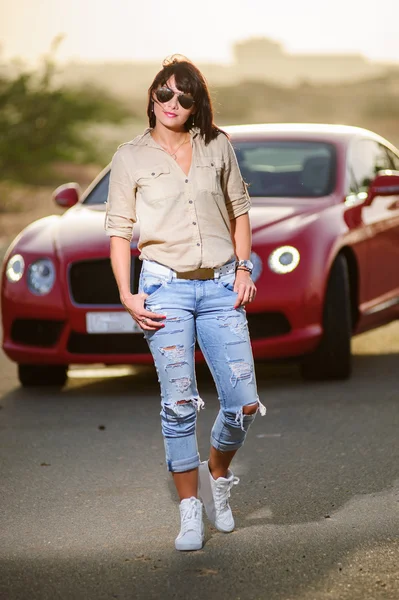 Woman poses in front of in red car. — Stock Photo, Image