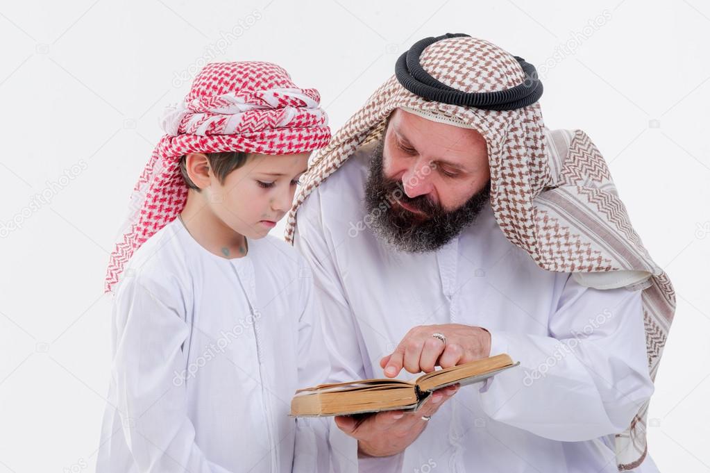 Arabic father teaching to read Koran his son.