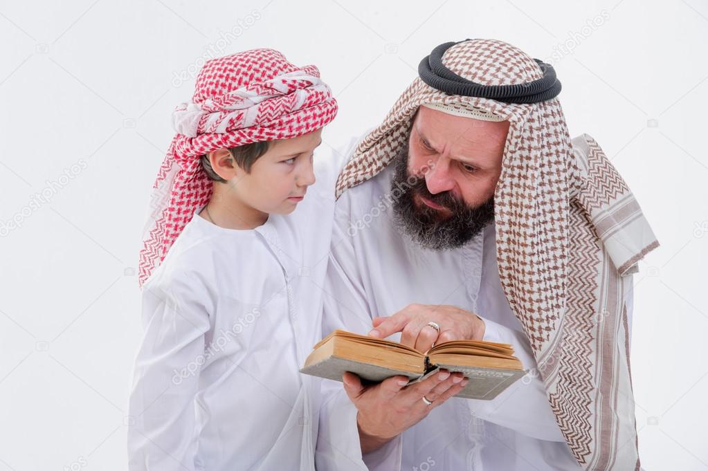 Arabic father teaching to read Koran his son.
