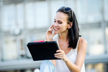 Genç ve güzel bir modern kadın pozlar tablet bilgisayar ile açık.