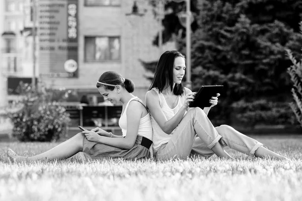 Madre está leyendo desde la tableta con su hija, sesión al aire libre — Foto de Stock
