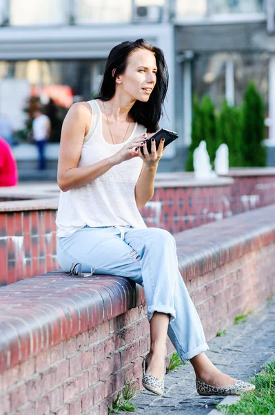 杨和美丽的现代商业女人姿势户外与智能手机. — 图库照片