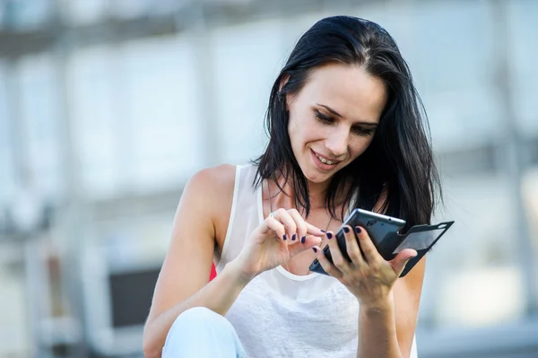 Yang och vackra moderna business woman poser utomhus med smart telefon. — Stockfoto