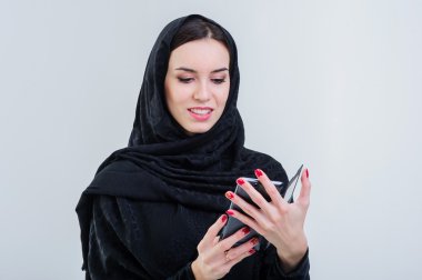 Pretty modern arabic woman playing on smart phone. clipart