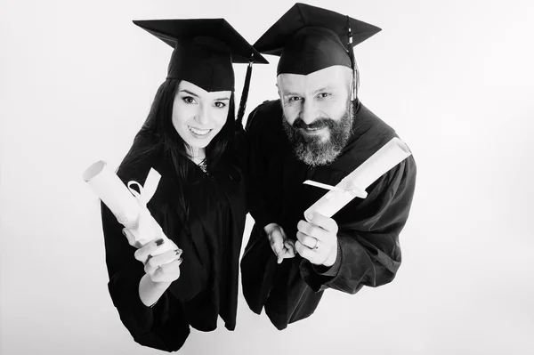 Двоє щасливих студентів-випускників ізольовані на сірому фоні чорно-білого — стокове фото