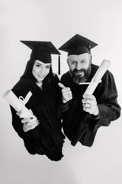 Twee gelukkige afstuderen volwassen studenten die geïsoleerd op grijze achtergrond zwart-wit — Stockfoto