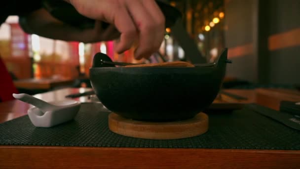 Ресторан японской кухни. Официант подает горячий суп в кастрюле крупным планом видео — стоковое видео