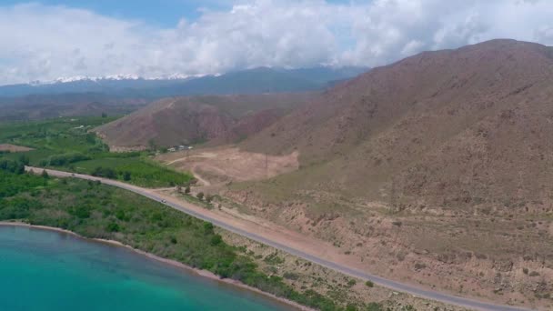 Vídeo aéreo da estrada rural ao longo da costa montanhosa do mar no dia ensolarado — Vídeo de Stock