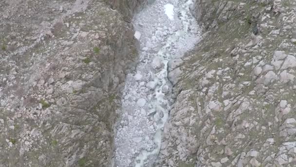 Tiro de inclinación aérea de corriente en el fondo del cañón de roca gris y las montañas — Vídeo de stock