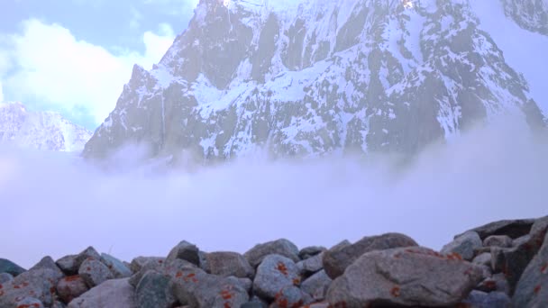 Escursioni su rocce contro montagne innevate nuvolose 4K video — Video Stock