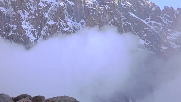 L'homme marche sur les rochers contre les montagnes couvertes de neige nuageuse 4K vidéo — Video