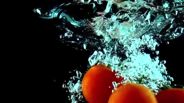 Manojo de tomates rojos maduros cae bajo el agua super slow motion shot — Vídeo de stock