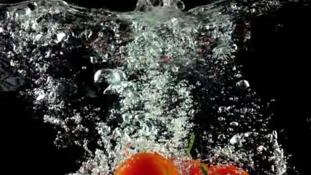 Mnoho zralých rajčat se zelenými listy spadá pod vodu super pomalý pohyb — Stock video