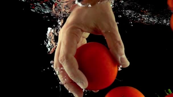 Super Zeitlupe Nahaufnahme von Hand, die Tomate unter Wasser greift und ergreift — Stockvideo