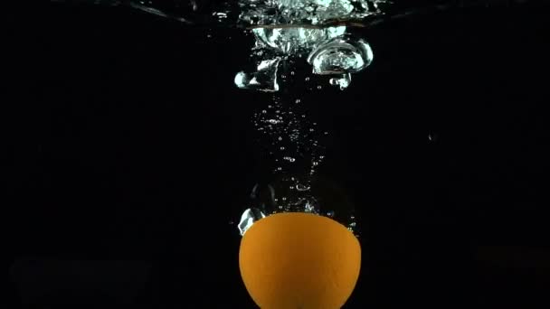 Metà dei lavandini arancioni in acqua contro lo sfondo nero super slow motion — Video Stock