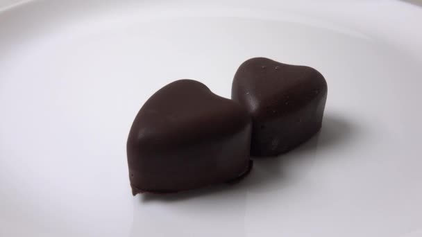 Close up 4K video of man hand putting heart shaped chocolates on white plate — Stock Video