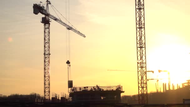 Siluetas de grúa transfiriendo placa de hormigón y trabajadores de la construcción. 4K — Vídeos de Stock