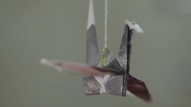 Бумажный кран оригами вращается на резьбе на сером фоне — стоковое видео