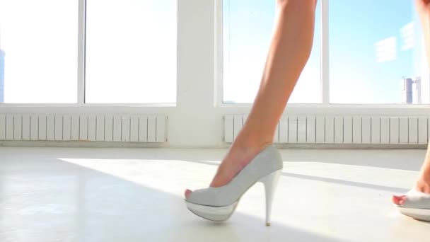 Дівчина в high heel взуття, ходьба проти панорамний сонячного вікна. Доллі постріл — стокове відео