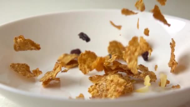 Płatki kukurydziane, suszone owoce i rozrzut z rodziny na białej płytce Super Slow Motion — Wideo stockowe