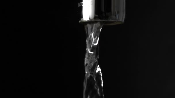 Macro Slow Motion shot van water dat loopt van de kraan tegen de zwarte achtergrond — Stockvideo