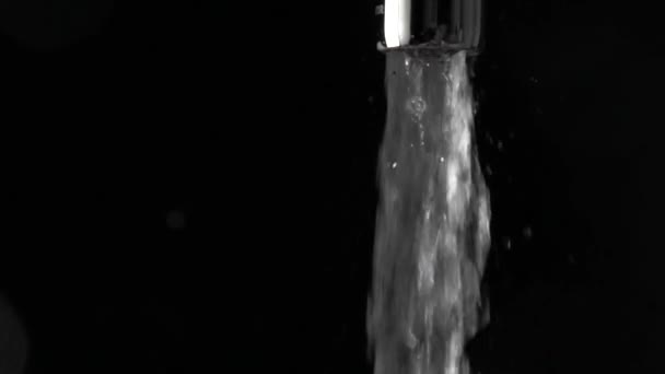 Супер замедленная съемка потока воды из крана на черном фоне — стоковое видео