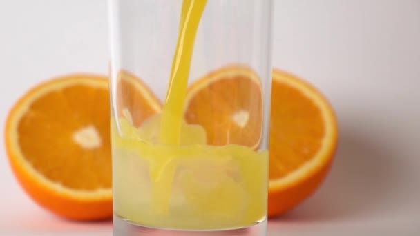 Zwei Orangenhälften und Orangensaft in Glas gegossen. Superzeitlupe — Stockvideo