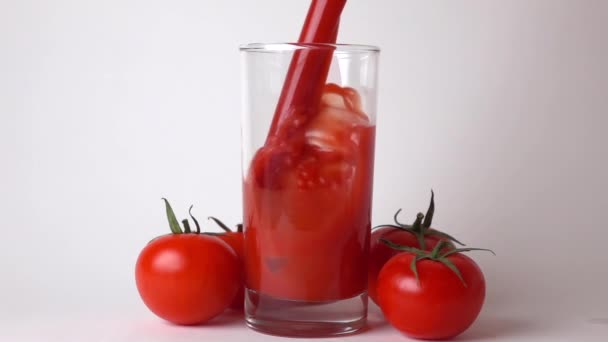 Celá červená zralá rajčata s listy a rajčatové šťávy nalije do sklenice — Stock video