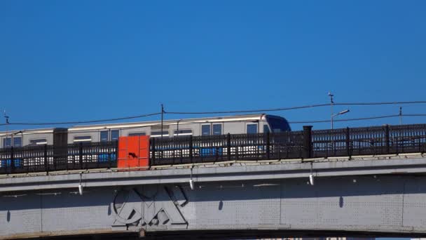 Moscow metro train with city emblem passing river bridge against blue sky, 4K — Stock Video