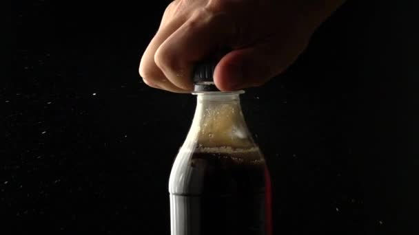 Homem abre garrafa de plástico cola com tampa de rosca. tiro em câmera lenta, fundo preto — Vídeo de Stock