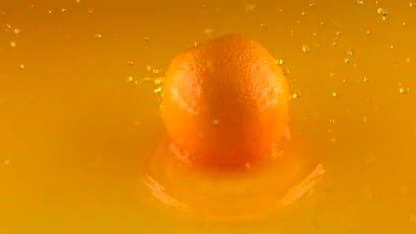 Laranja madura inteira batendo na superfície do suco de laranja e recuperando. Tiro em câmara lenta — Vídeo de Stock