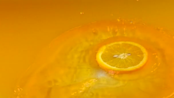 A fatia de laranja atinge a superfície do suco de laranja. Tiro em câmara lenta — Vídeo de Stock