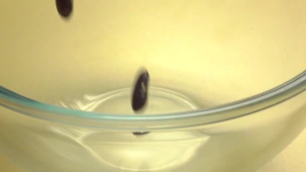 Zwarte bonen te gieten in een glazen kom. Super SlowMotion macro video — Stockvideo