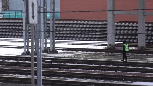 Trabajador ferroviario irreconocible contra pila de nuevos rieles y ataduras. Imágenes 4K — Vídeos de Stock