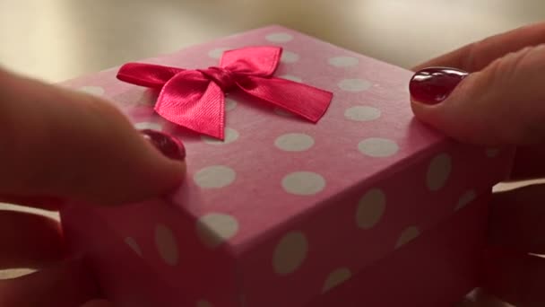 Flicka händer med rött manikyr placera rosa och vit prickiga presentförpackning på bord — Stockvideo