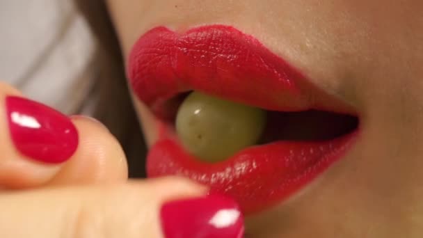 Giovane donna con manicure rossa e labbra rosse mangiare uva verde, estremo primo piano — Video Stock