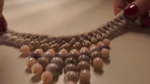 Belle femme mains mettant collier beige vers le bas sur la table — Video