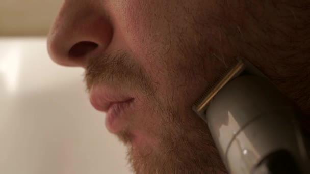 Jonge man met behulp van zijn trimmer te snijden zijn korte baard. 2 close-up van video's in 1 — Stockvideo