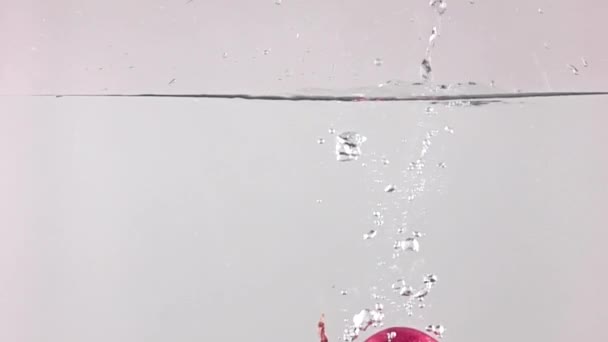 Super slow motion video: falling red onion and splashes of water — Stock Video