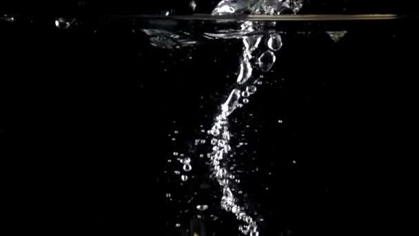Câmera de alta velocidade tiro: salpicos de cebola na água, fundo preto — Vídeo de Stock