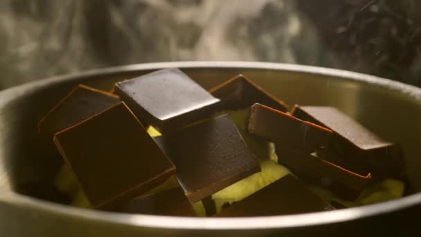 Кусочки шоколадного батончика и масло, расплавленные в кастрюле, крупным планом видео — стоковое видео
