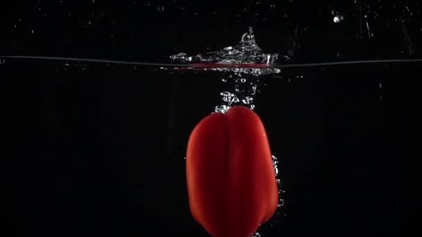 Pimiento rojo cayendo en el agua, fondo negro super slow motion shot — Vídeo de stock